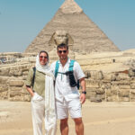 Couple of tourists enjoying their vacation posing in front of the great sphinx of giza in egypt